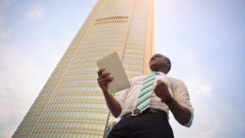 executive stands in front of skyscraper